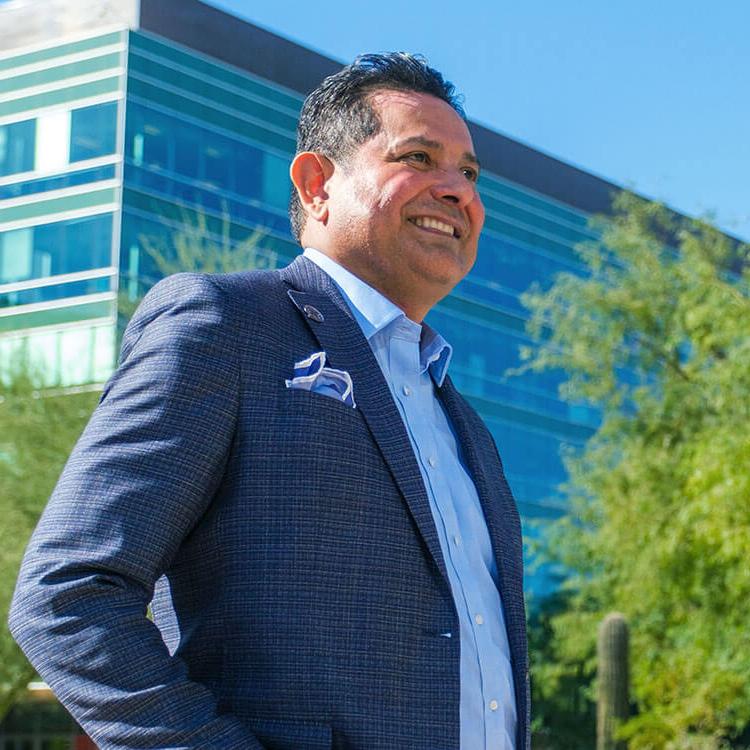 Thomas Leon smiling, wearing a business suit - feeling confident